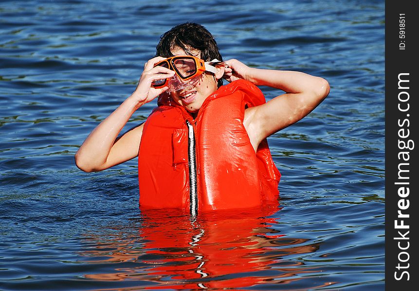 The boy with a life-jacket and a diving mask having fun in a small lake late afternoon. The boy with a life-jacket and a diving mask having fun in a small lake late afternoon.