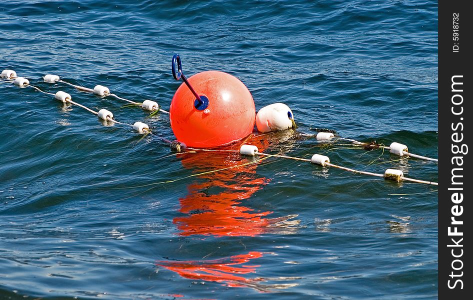 Orange buoy on a string floating together with small white of cork