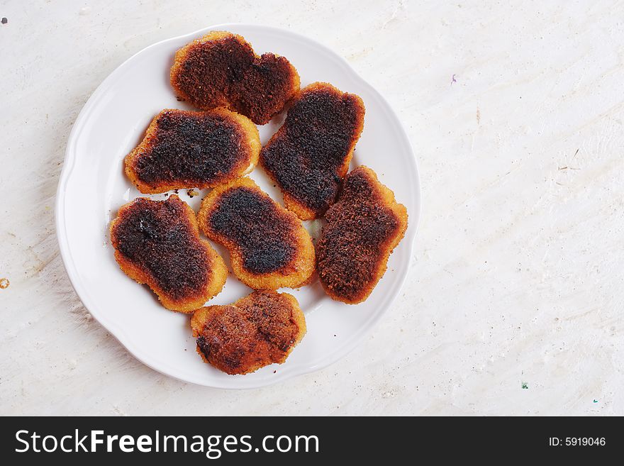 Slightly burnt chicken cutlets on the plate. Slightly burnt chicken cutlets on the plate.