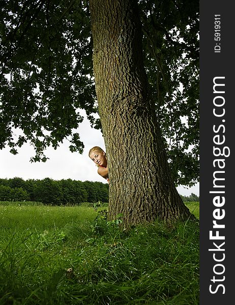 Girl hideing behind a tree.