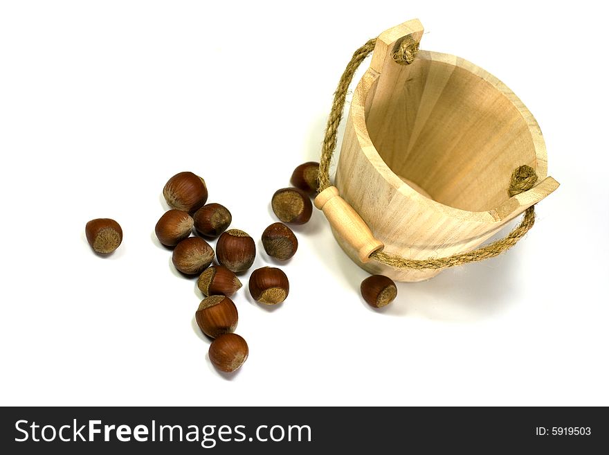 Hazelnuts and empty wooden busket on white background