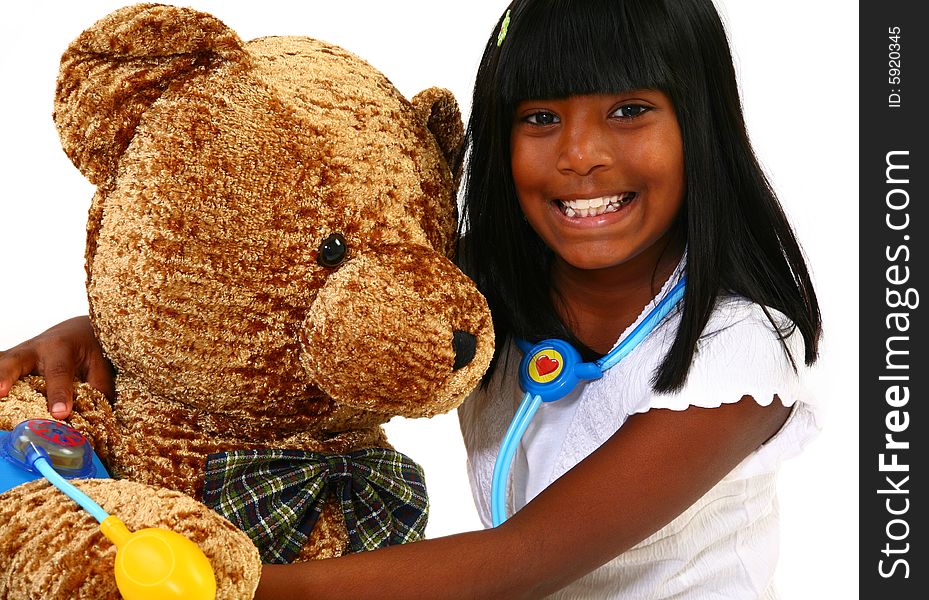 Beautiful 10 year old Indian girl playing doctor to a giant teddy bear. Beautiful 10 year old Indian girl playing doctor to a giant teddy bear.