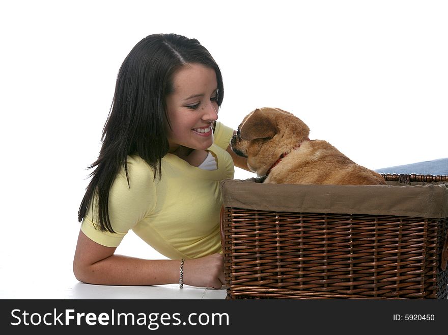 Cute teen leaning in toward little pug dog in wicker basket. Cute teen leaning in toward little pug dog in wicker basket