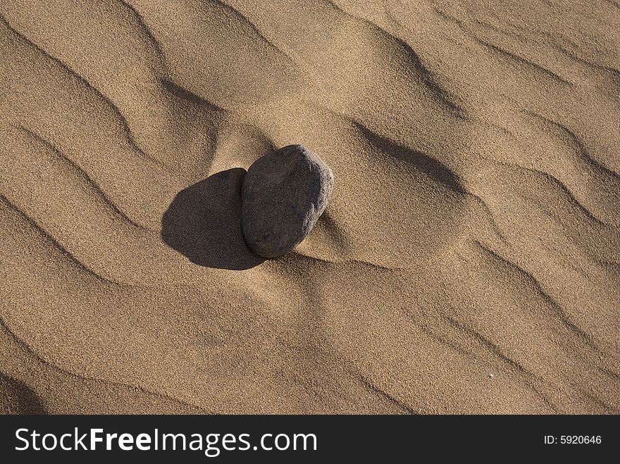 A weathered stone on a desert sand dune. A weathered stone on a desert sand dune