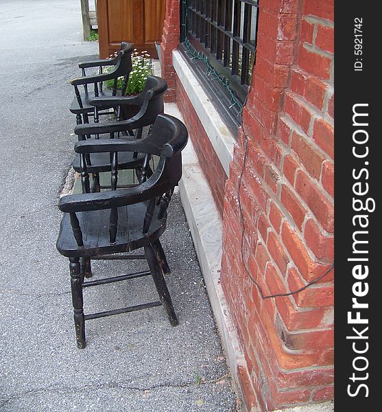 A row of chairs sit in front of a brick wall just
waiting for anyone who would like to sit a spell.