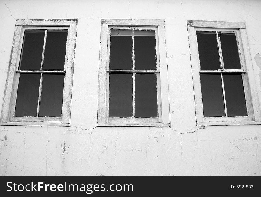 Black and white detail of three windows on the side of an abandoned building. Black and white detail of three windows on the side of an abandoned building