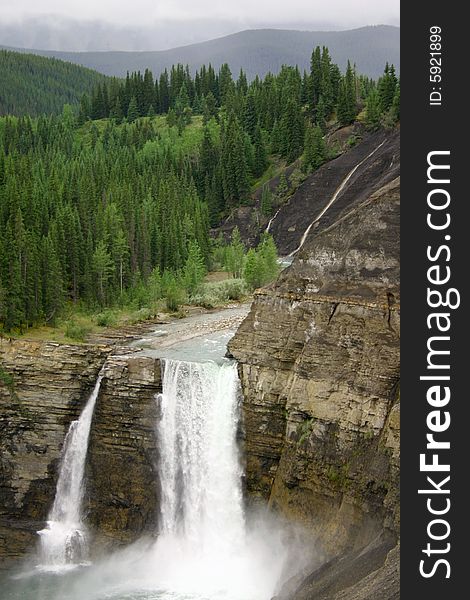 A powerful twin waterfall plunging over a cliff in the Canadian Rockies