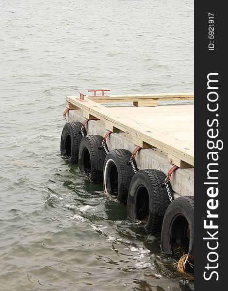 Detail of old tires protecting a boat dock floating on a turbulent lake