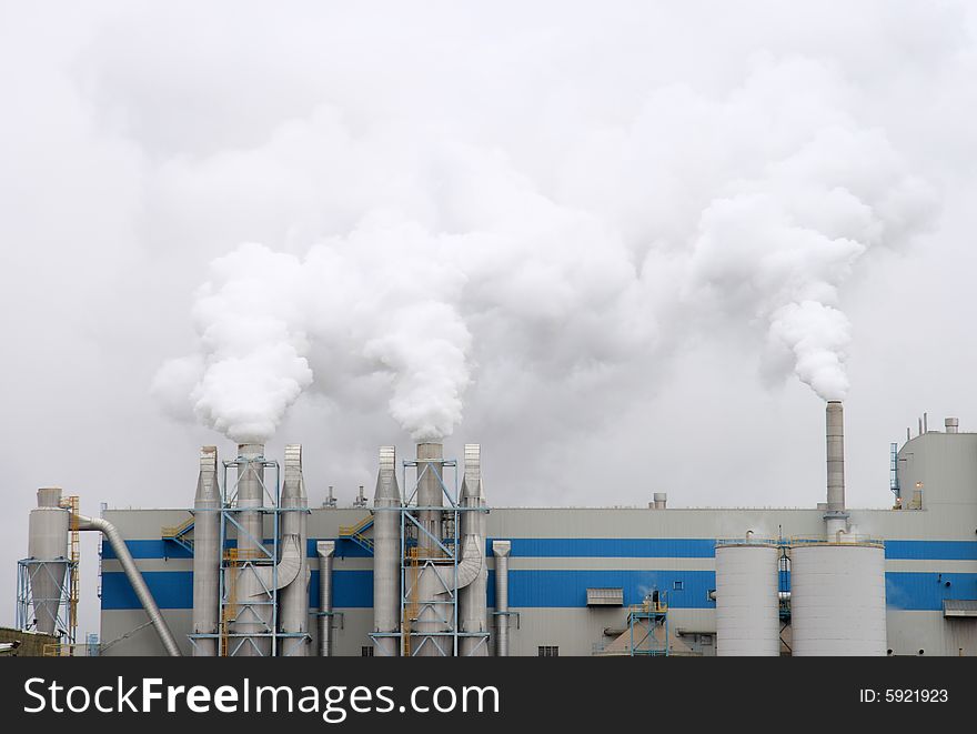 Detail of smoke pouring out of the stacks on a large factory. Detail of smoke pouring out of the stacks on a large factory