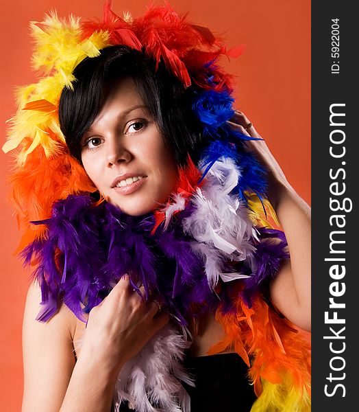 Beautiful  woman wearing feathers against orange background. Beautiful  woman wearing feathers against orange background