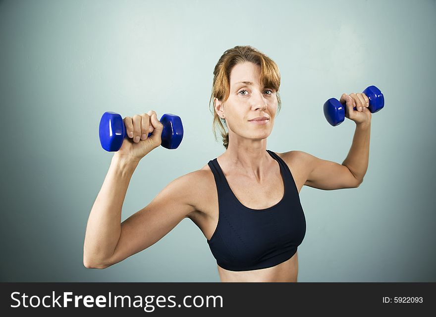 Pretty athletic woman working out with dumbbells. Pretty athletic woman working out with dumbbells