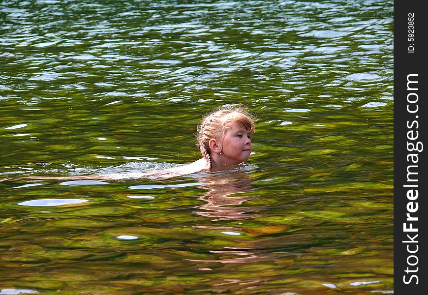 Small girl swims in river with water beautiful green hue. Sunny day, summer. Fussian Far East, Primorye. Small girl swims in river with water beautiful green hue. Sunny day, summer. Fussian Far East, Primorye.