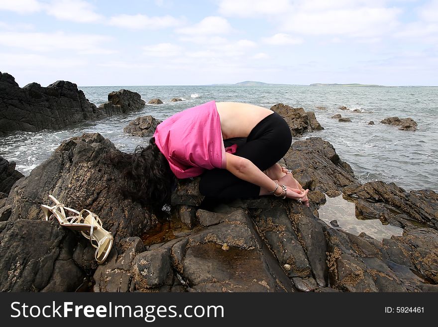 Beautiful woman meditating on the rocks in ireland with her eyes closed,  showing a healthy way to live a happy and relaxed lifestyle in a world full of stress. Beautiful woman meditating on the rocks in ireland with her eyes closed,  showing a healthy way to live a happy and relaxed lifestyle in a world full of stress