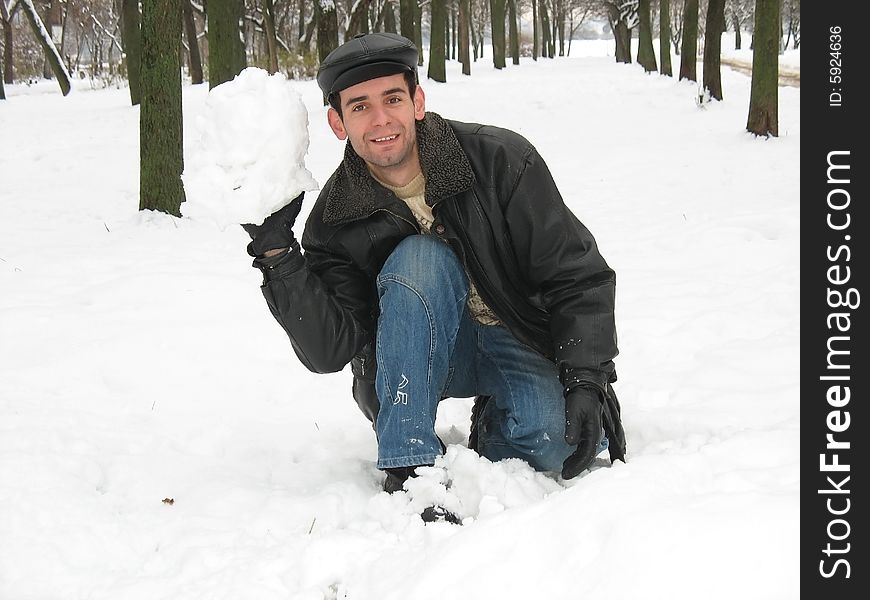 The young man is playing snowballs in the park. The young man is playing snowballs in the park