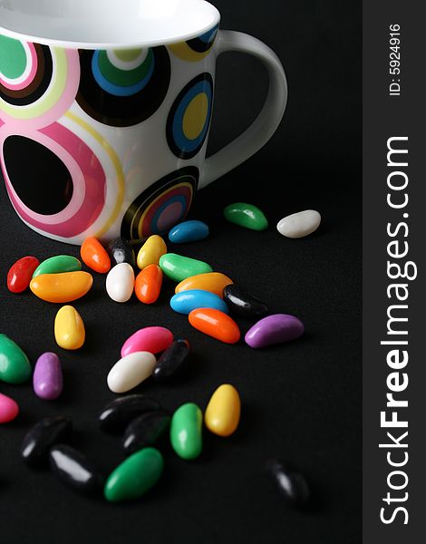 Jelly beans and a mug on a black background. Jelly beans and a mug on a black background