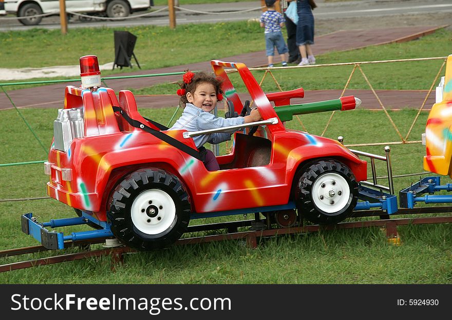 Glad child rides on round-robins on colorful baby car.