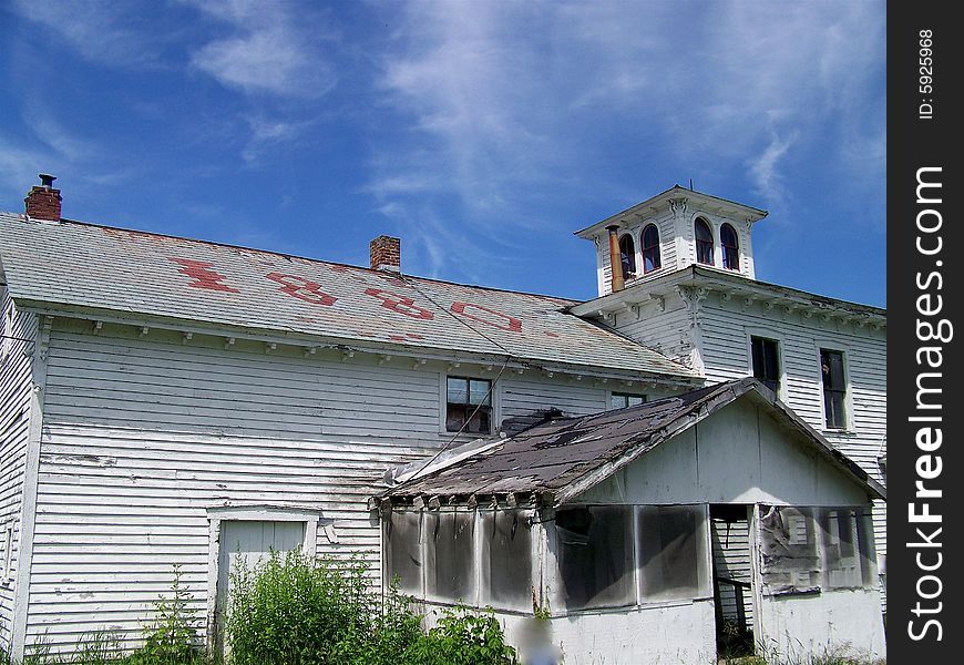 An old deserted farmhouse built in 1880 stands against the blue sky. An old deserted farmhouse built in 1880 stands against the blue sky.