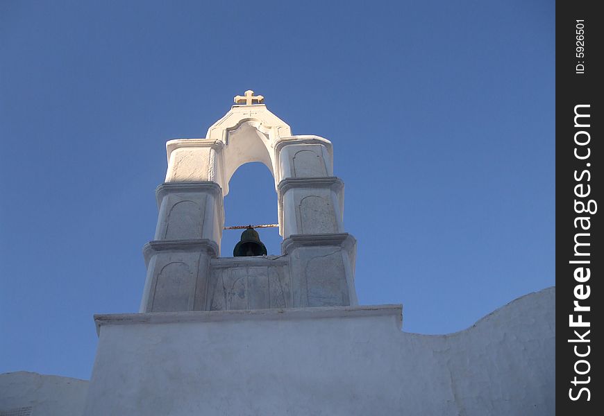 Sunshine on the cross of a bell tower of Greek Chapel - catching the day's last rays of sun on Mykonos Island, Greece, Europe. Sunshine on the cross of a bell tower of Greek Chapel - catching the day's last rays of sun on Mykonos Island, Greece, Europe