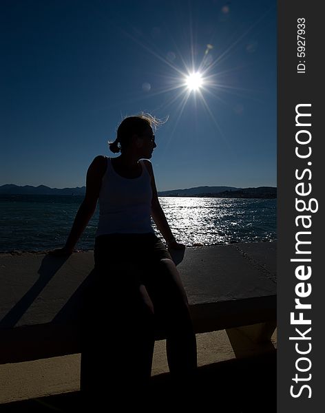 Woman leaning on balustrade in front of the sea and the sun. Woman leaning on balustrade in front of the sea and the sun