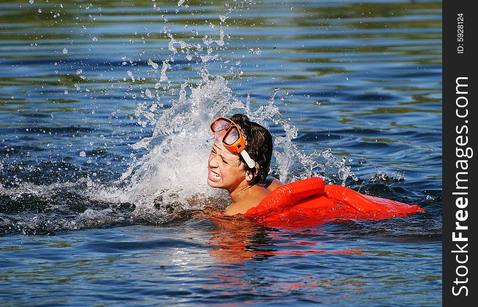 The boy with a life-jacket making splashes in a lake. The boy with a life-jacket making splashes in a lake.