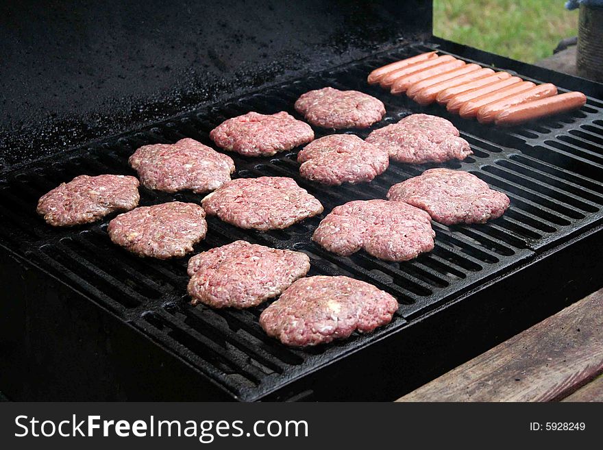 Some hambugers and hotdogs are put on the grill for a cookout. Some hambugers and hotdogs are put on the grill for a cookout.