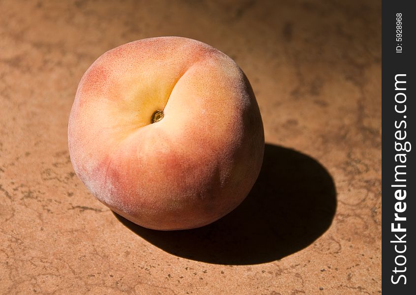 A single peach in the sun.