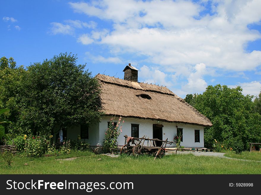 The ancient, country house under a straw roof worth near trees. The ancient, country house under a straw roof worth near trees