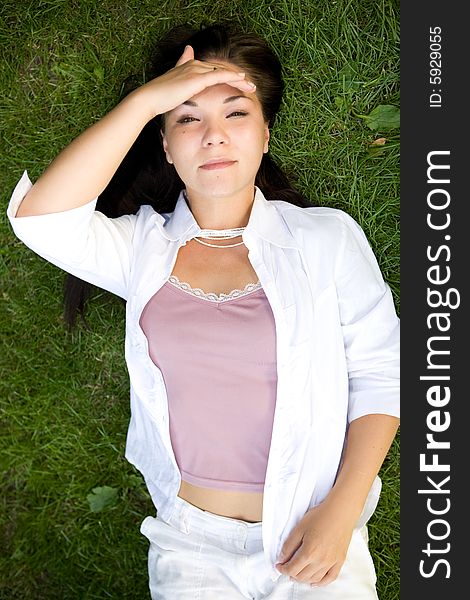 Happy brunette woman lying on grass. Happy brunette woman lying on grass