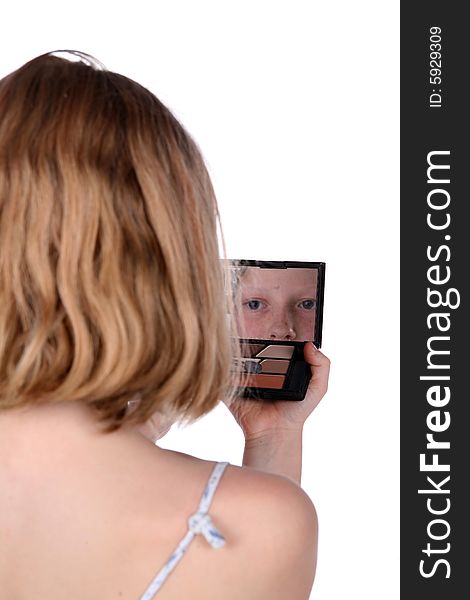 Young girl looking into mirrored makeup compact