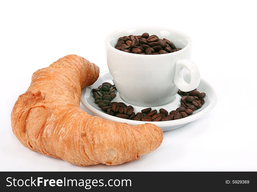 Croissant and cup with coffee beans