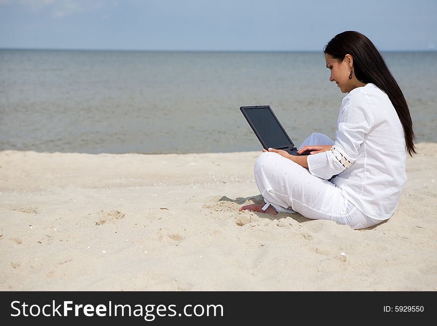 Attractive brunette woman with laptop on the beach