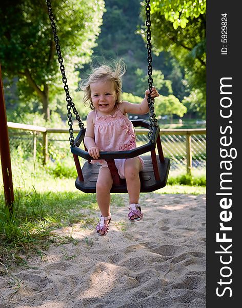 Cute one year old girl having fun on a swing