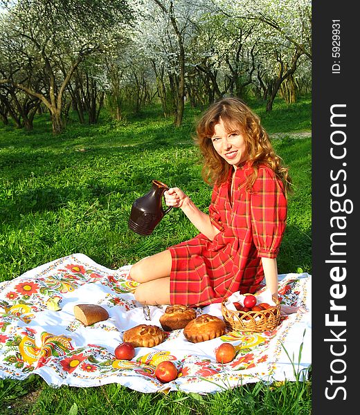 The young red-haired woman is having a picnic in the spring garden. The young red-haired woman is having a picnic in the spring garden