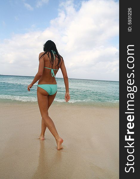 A girl in a swimsuit walking on the beach. A girl in a swimsuit walking on the beach