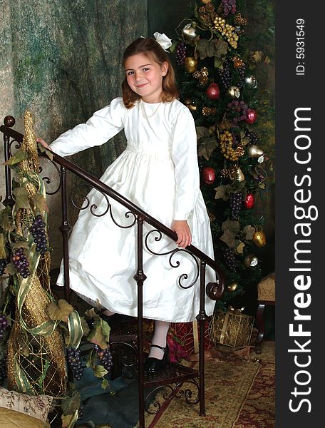 School aged girl on stairs in front of Christmas tree