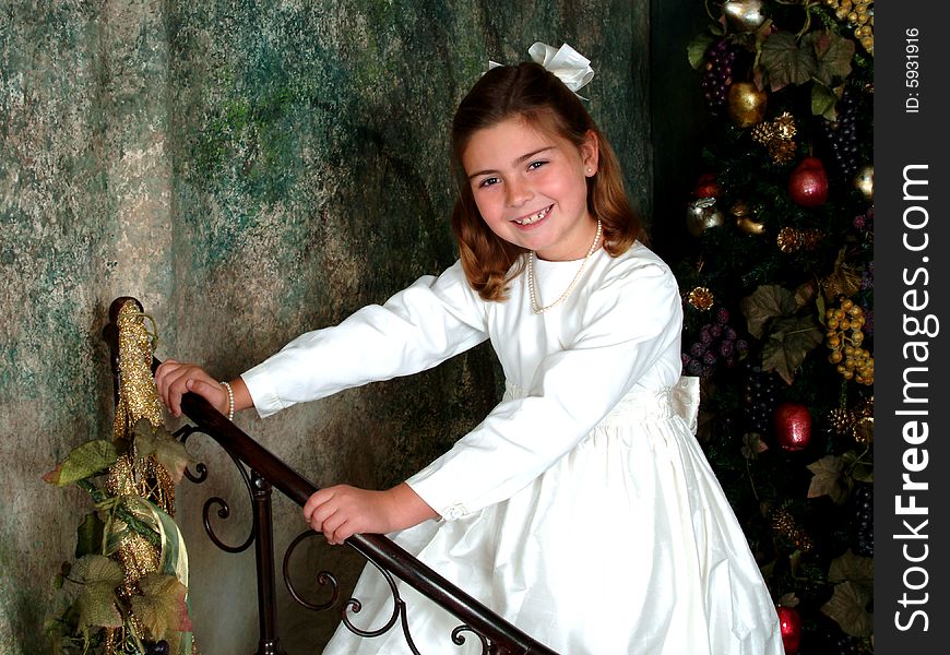 School aged girl holding metal rail in front of Christmas tree. School aged girl holding metal rail in front of Christmas tree