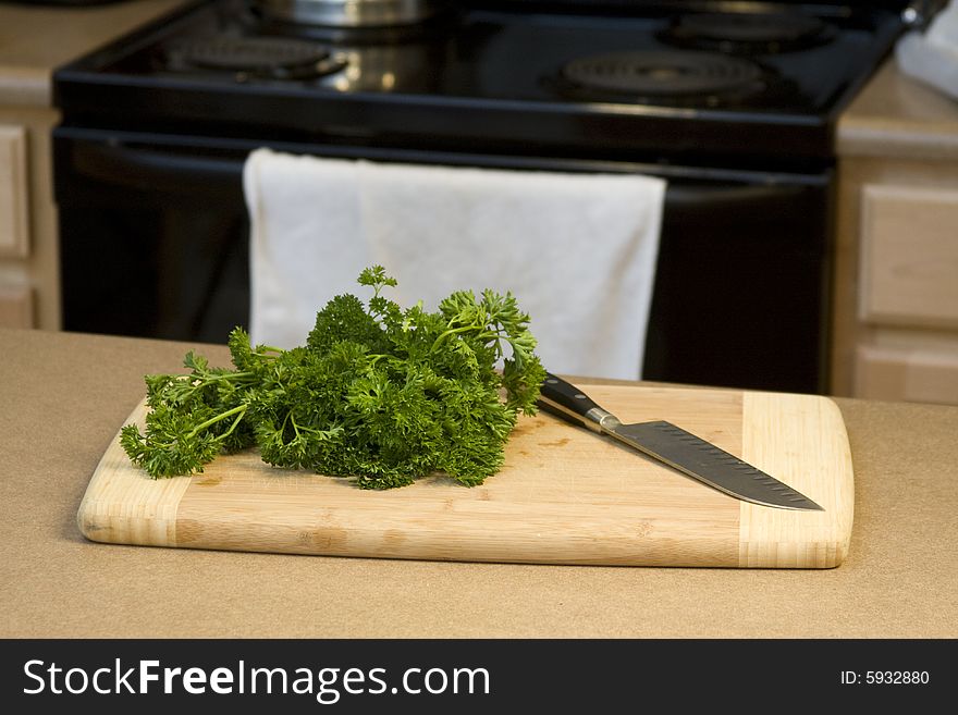 Fresh parsley on a bamboo cutting board with a chef's knife. Fresh parsley on a bamboo cutting board with a chef's knife.
