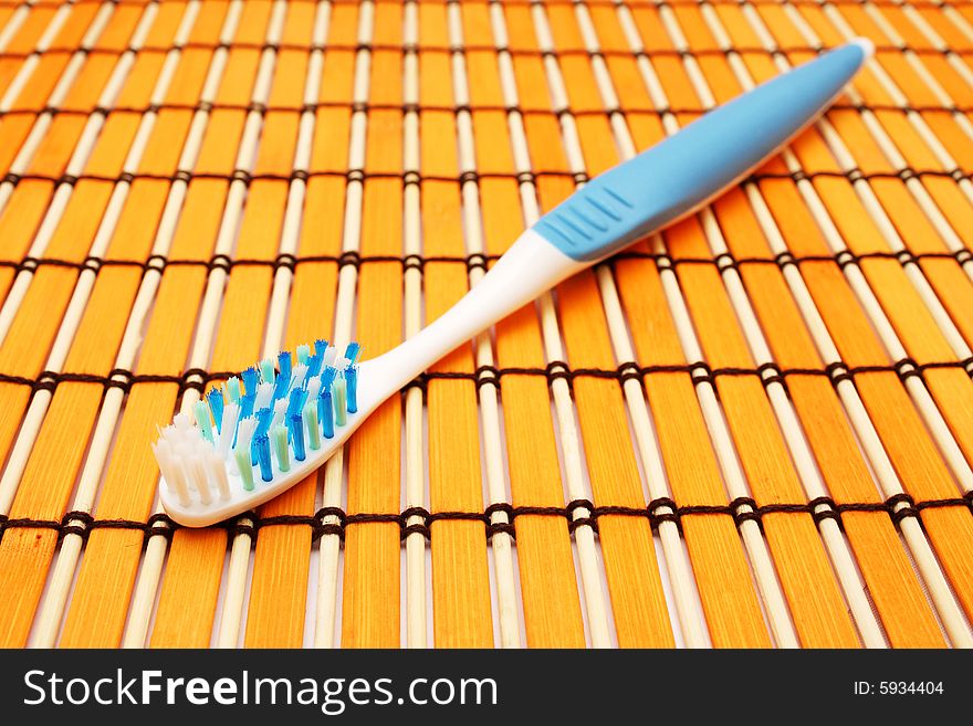 A blue white tooth brush put on orange mat.