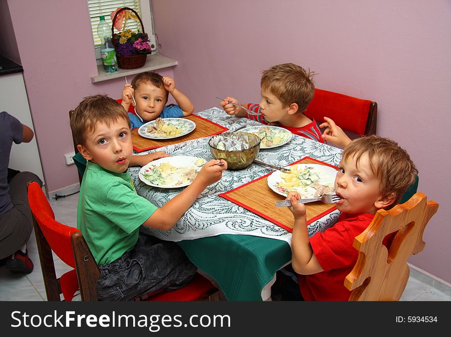 Four young boys indoors eating