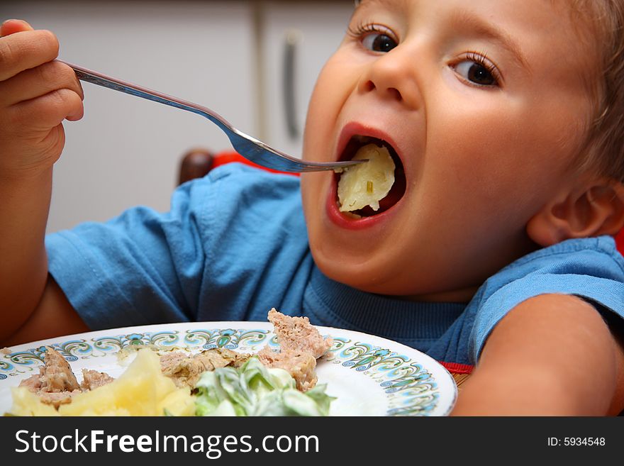 Young boy indoors eating dinner