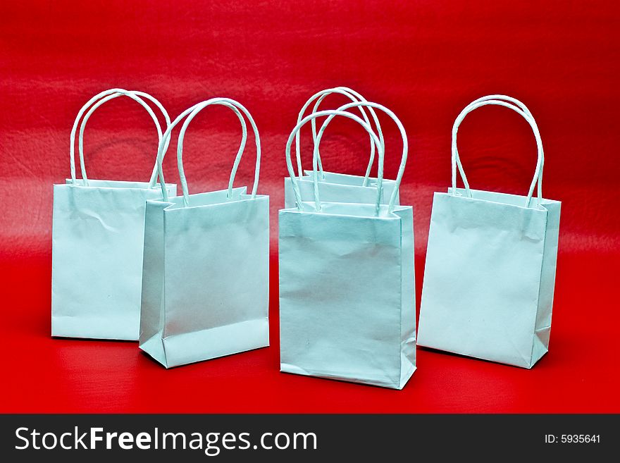 Five white gift bags against a red background. Five white gift bags against a red background.