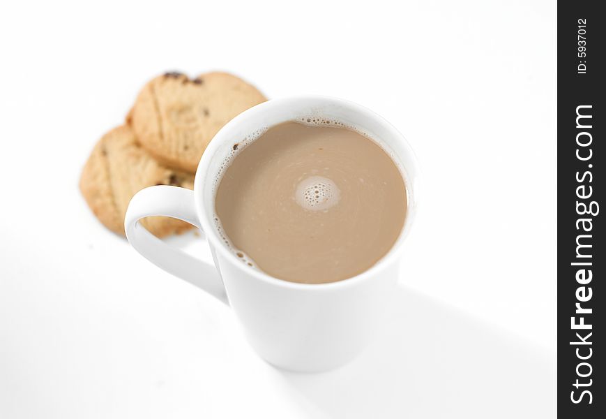 Seen from above a stylized and high key view of a mug of white coffee and two biscuits on a clean white background. Seen from above a stylized and high key view of a mug of white coffee and two biscuits on a clean white background.