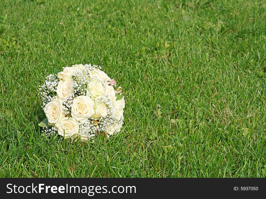 Wedding bouquet from white roses on a green grass