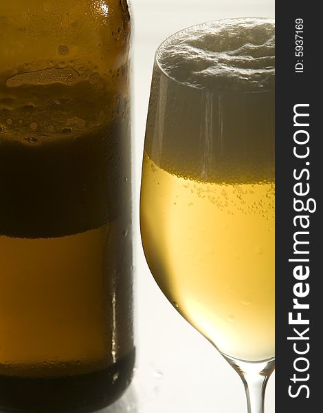 A open beer-bottle is standing next to an empty beer-glass. A open beer-bottle is standing next to an empty beer-glass