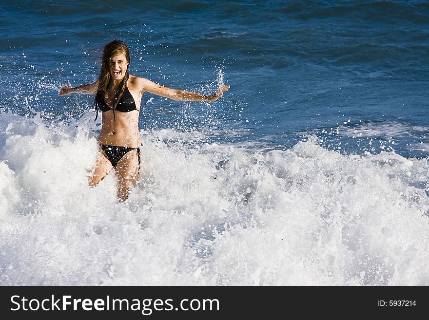 Young bikini woman playing with waves at the beach.