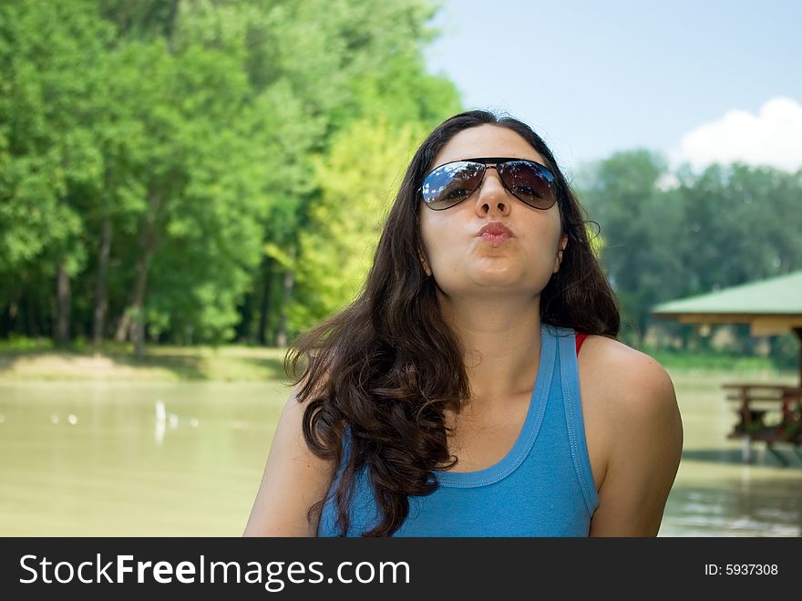 A pretty girl, sitting on a bench near a lake, enjoying the time outdoors. A pretty girl, sitting on a bench near a lake, enjoying the time outdoors