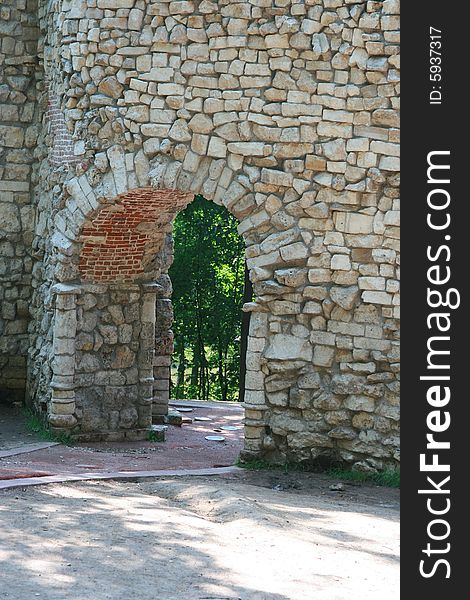 Old stone wall with an arch pass inside