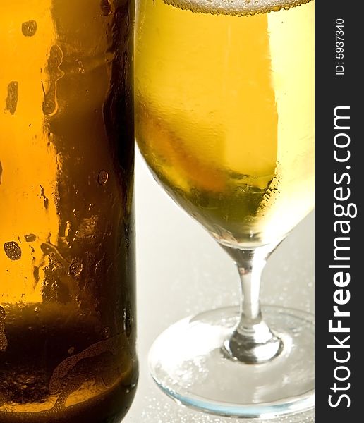A open beer-bottle is standing next to an empty beer-glass. A open beer-bottle is standing next to an empty beer-glass