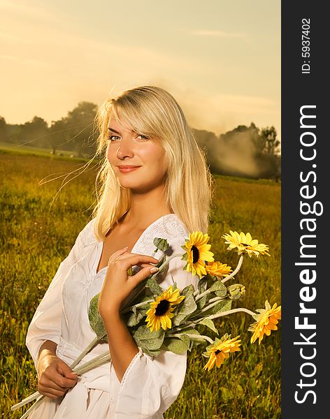 Young beautiful woman with a bouquet of sunflowers in thr field at sunset. Young beautiful woman with a bouquet of sunflowers in thr field at sunset