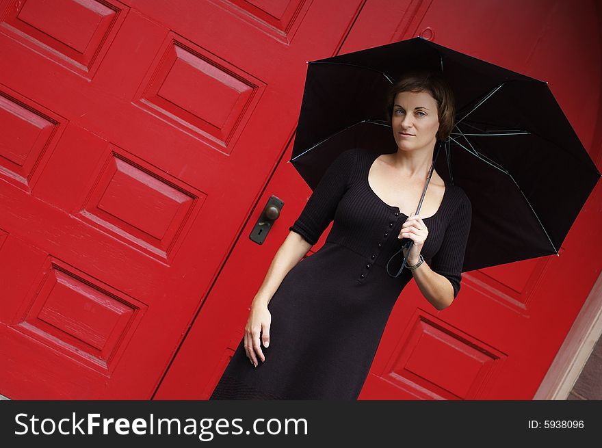 Woman with umbrella in front of red doors.